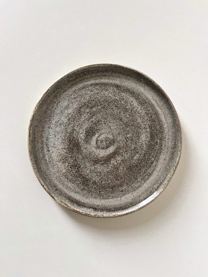Handmade plate from mixed clay and porcelain with a speckled, stone-like surface and a visible spiral