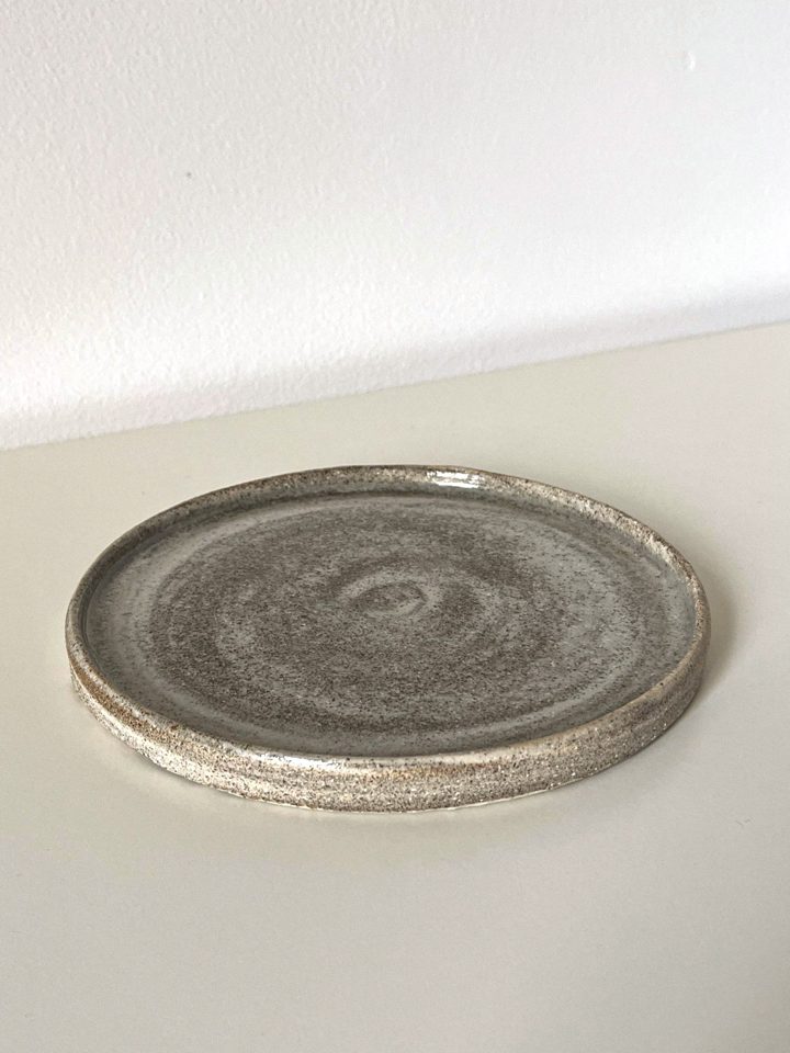 Handmade plate from mixed clay and porcelain with a speckled, stone-like surface and a visible spiral, second view