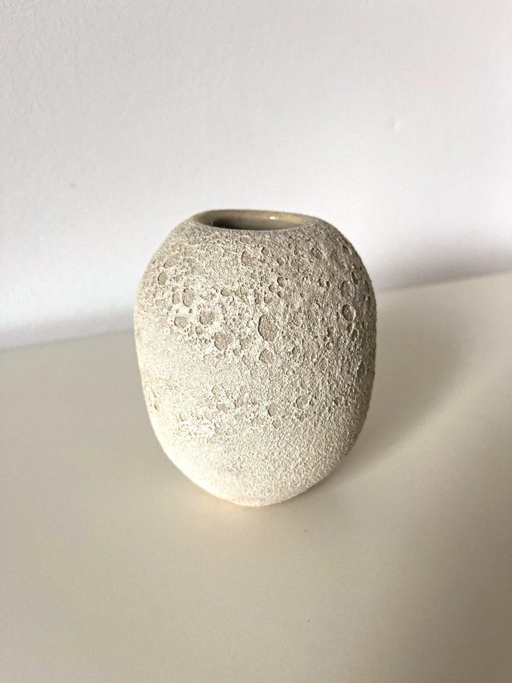 Small pale ceramic vase with a pitted, moon-like crater texture
