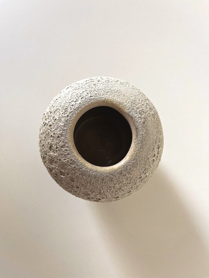 Small pale ceramic vase with a pitted, moon-like crater texture, second view