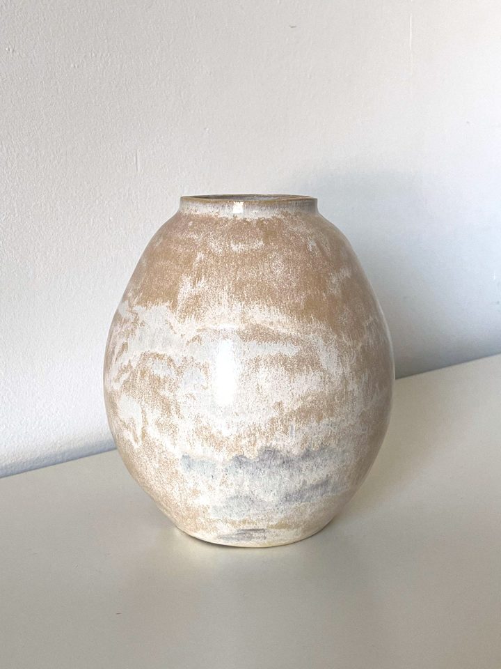 Rounded handmade ceramic vase in warm sand clay with a pale, brushed white glaze